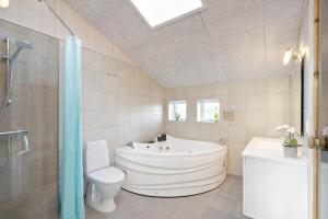 a bathroom with a tub and a toilet and a shower at 135-Ringkobing-Sortebaerdalen-51 in Kryle +35 photos