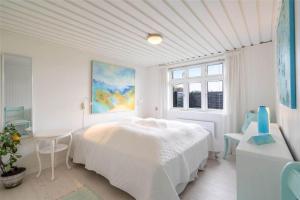 a white bedroom with a bed and a table at 085-Ringkobing-Nordsovej-68 in Søndervig