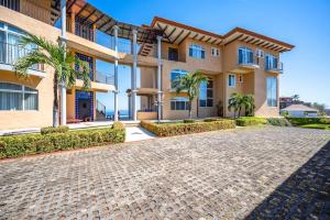 a large apartment building with a cobblestone driveway at Corona del Mar #6 in Ocotal