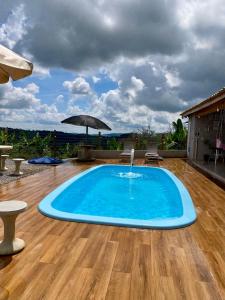 a swimming pool on a wooden floor with an umbrella at Chalés Sonho Meu in Munhoz