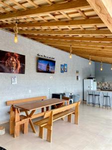 a wooden table and bench in a room with a tv at Chalés Sonho Meu in Munhoz