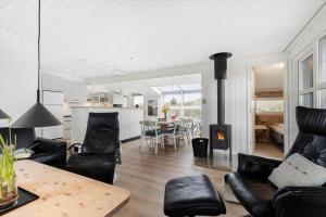 a living room with black leather furniture and a fireplace at 208-Ringkobing-Fladsbjergvej-226 in Klegod