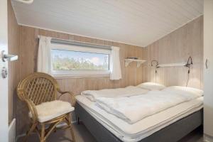 a bed in a room with a chair and a window at 208-Ringkobing-Fladsbjergvej-226 in Klegod