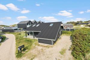 a small house with a black roof on a beach at 1130-Ringkobing-Sletten-18 in Søndervig