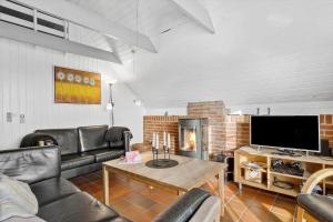 a living room with leather furniture and a fireplace at 290-Ringkobing-Nordso-Ferievej-50 in Nørre Lyngvig