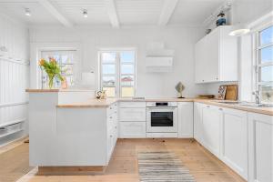 a white kitchen with white cabinets and a wooden floor at 1154-Ringkobing-Nordsovej-50 in Søndervig