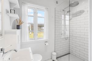 a white bathroom with a sink and a shower at 1154-Ringkobing-Nordsovej-50 in Søndervig +29 photos