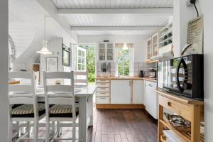a kitchen with a table and chairs and a microwave at 123-Ringkobing-Granalle-3 in Nørby