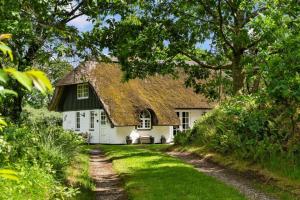 a white house with a grass roof with a dirt road at 123-Ringkobing-Granalle-3 in Nørby