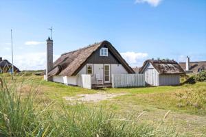 a house with a thatched roof on a field at 207-Ringkobing-Nordso-Ferievej-27 in Nørre Lyngvig