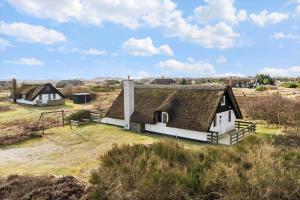 an old house with a thatched roof in a field at 2254-Ringkobing-Nordso-Ferievej-52 in Nørre Lyngvig