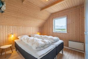a large bed in a wooden room with a window at 152-Ringkobing-Regnspovedalen-6 in Nørby