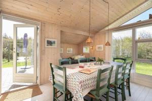 a dining room with a table and green chairs at 078-Ringkobing-Rorsangervej-11 in Nørby