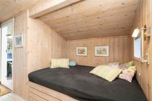 a bed in a small room with wooden walls at 078-Ringkobing-Rorsangervej-11 in Nørby