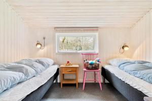 two beds in a room with a table and a chair at 095-Ringkobing-Risbjergvej-12 in Nørby