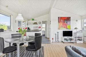 a dining room with a table and chairs and a kitchen at 235-Ringkobing-Vestklitvej-11 in Klegod