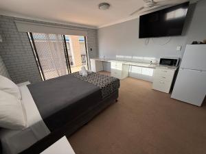 a bedroom with a large bed and a kitchen at Surf Beach Motel Tweed in Tweed Heads