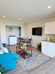 a living room with a blue couch and a table at Lakaz Beach house in Omokoroa