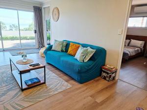 a living room with a blue couch and a table at Lakaz Beach house in Omokoroa