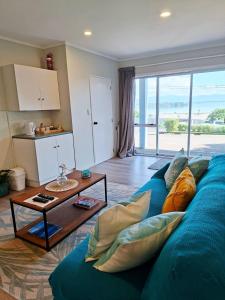 a living room with a blue couch and a table at Lakaz Beach house in Omokoroa