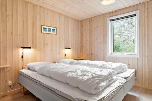 a bedroom with a bed with white sheets and a window at 127-Ringkobing-Birkealle-1 in Nørby