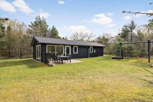 a black shed with a picnic table in a yard at 127-Ringkobing-Birkealle-1 in Nørby