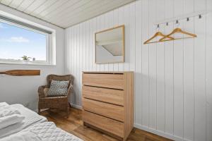 a bedroom with a bed and a dresser and a window at 286-Ringkobing-Vestklitvej-14 in Klegod