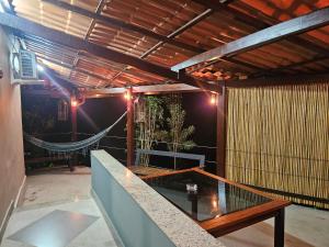 a patio with a glass table and a hammock at Green Area House in Abraão