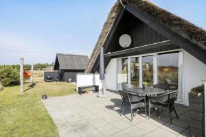 a patio with a table and chairs in front of a house at 273-Ringkobing-Nordso-Ferievej-28 in Nørre Lyngvig