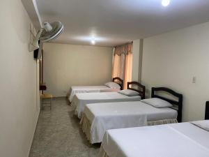 eine Reihe von vier Betten in einem Zimmer in der Unterkunft Hotel Nova Real in Ibagué