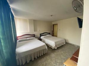 ein Zimmer mit zwei Betten in einem Zimmer in der Unterkunft Hotel Nova Real in Ibagué
