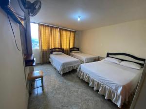 ein Hotelzimmer mit zwei Betten und einem Fenster in der Unterkunft Hotel Nova Real in Ibagué