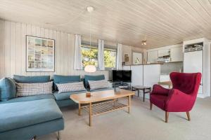 a living room with a blue couch and red chairs at 1082-Ringkobing-Milevej-11 in Klegod