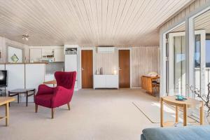 a living room with a red chair and a kitchen at 1082-Ringkobing-Milevej-11 in Klegod