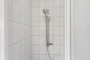 a shower with a hose in a white tiled bathroom at 1082-Ringkobing-Milevej-11 in Klegod +23 photos
