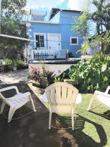 a yard with two white chairs and a blue house at Powell's guesthouse in Santa Cruz