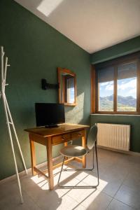 a desk with a computer on a green wall at Coronel Somiedo by Unusual Hotels in El Puerto de Somiedo