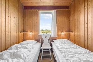 a bedroom with two beds and a chair and a window at 201-Ringkobing-Fladsbjergvej-234 in Klegod
