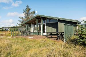 a small green building with a table and chairs on a deck at 201-Ringkobing-Fladsbjergvej-234 in Klegod +19 photos