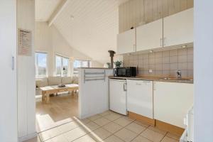 a kitchen with white cabinets and a living room at 120-Ringkobing-Sletten-15 in Søndervig