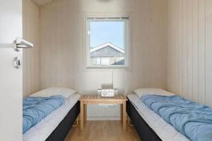 two beds in a room with a table and a window at 120-Ringkobing-Sletten-15 in Søndervig