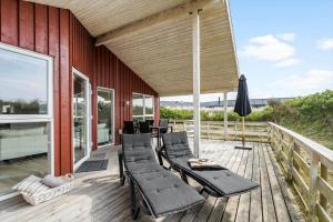 a deck with chaise lounge chairs and an umbrella at 120-Ringkobing-Sletten-15 in Søndervig