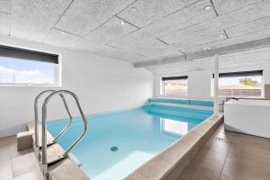 a swimming pool with blue water in a room with windows at 292-Ringkobing-Vestklitvej-12 in Klegod