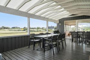 a dining room with a table and chairs and windows at 268-Ringkobing-Lyngvejen-63 in Klegod