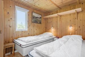 two beds in a wooden room with a window at 268-Ringkobing-Lyngvejen-63 in Klegod