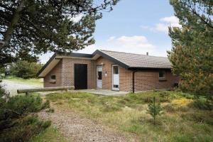 a small brick house in a field with trees at 2253-Ringkobing-Fladsbjergvej-234-E in Klegod