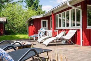 a group of chairs on a deck next to a red building at 1134-Ringkobing-Egernvej-12 in Nørby
