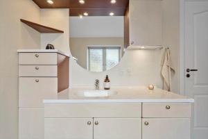 a white bathroom with a sink and a mirror at 1177-Ringkobing-Anders-Juhls-Vej-10 in Søndervig +36 photos