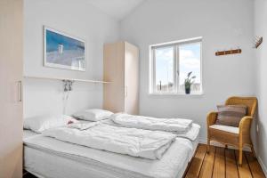 a bedroom with a bed and a chair and a window at 1177-Ringkobing-Anders-Juhls-Vej-10 in Søndervig