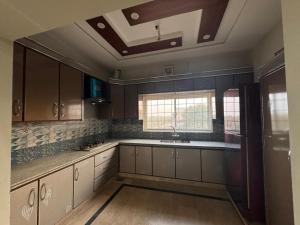 a kitchen with white cabinets and a sink and windows at 6-BedRoom house in Bahria in Lahore